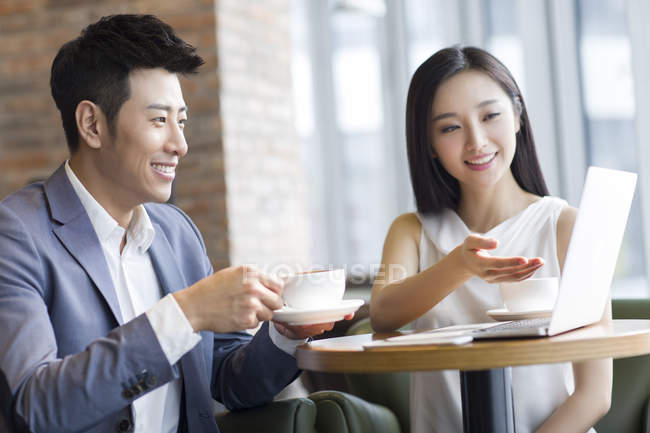 Asiático hombre y mujer trabajando con el ordenador portátil en la cafetería - foto de stock