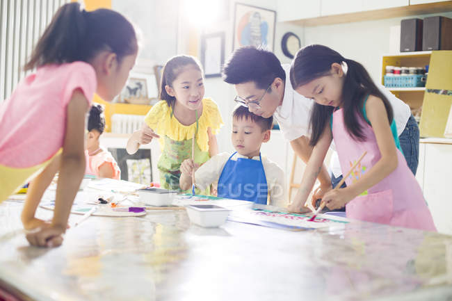 Crianças chinesas pintando em aula de arte com professor — Fotografia de Stock