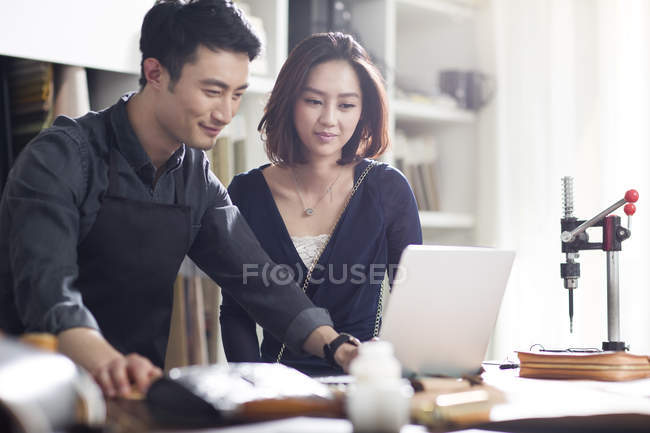 Asian craftsman and customer in studio with laptop — Stock Photo