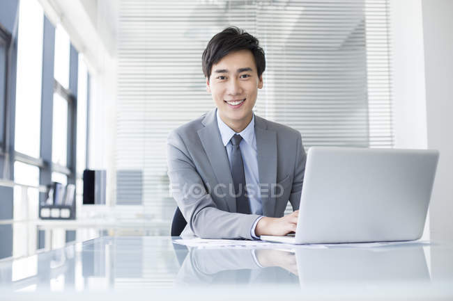 Hombre de negocios chino usando portátil en la oficina - foto de stock