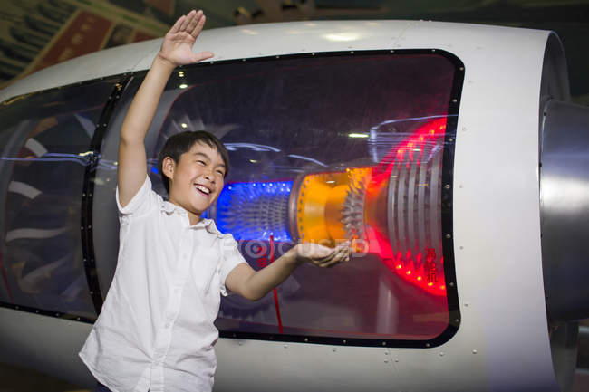 Garçon chinois posant avec moteur à réaction dans le musée — Photo de stock