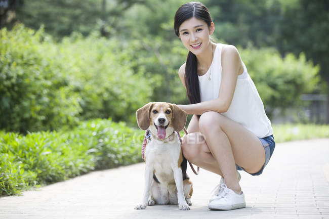 Young Chinese woman posing with cute beagle in park — Stock Photo