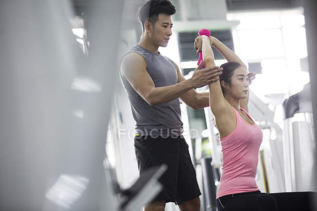 Mulher asiática trabalhando com treinador no ginásio — Fotografia de Stock