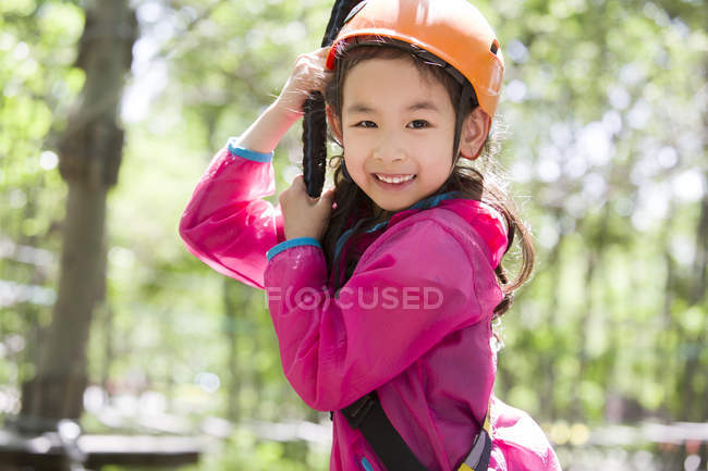 Chinese girl hanging on rope in tree top adventure park — Stock Photo