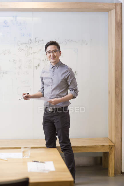 Trabajador de oficina chino de pie frente a la pizarra - foto de stock