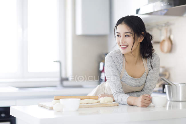 Азиатка пьет кофе на кухне — стоковое фото