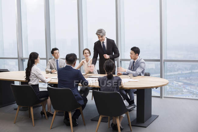 Equipe de negócios chinesa tendo reunião com parceiros estrangeiros na sala de bordo — Fotografia de Stock