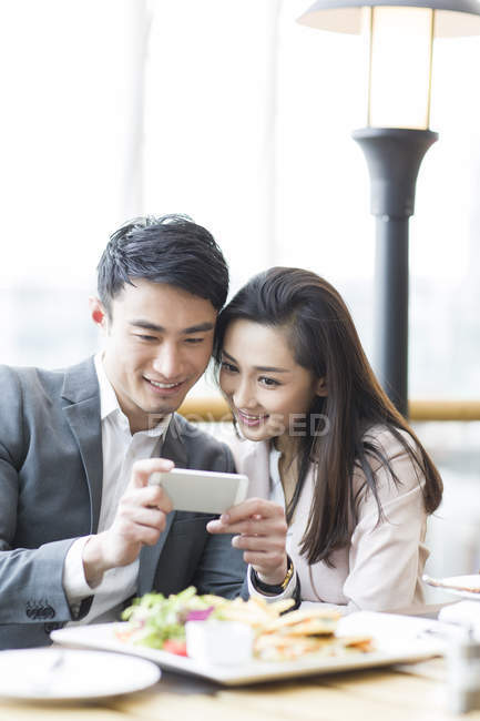 Китайская пара фотографирует еду в ресторане — стоковое фото