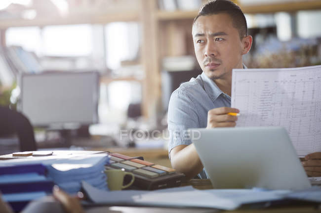 Male asian architect holding blueprint in office — Stock Photo
