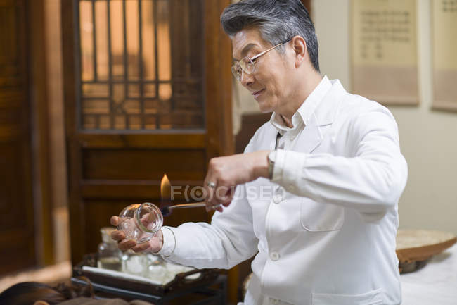 Médico chino maduro preparando terapia de ventosas - foto de stock
