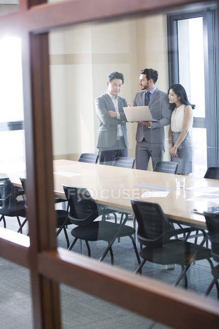 Business people using laptop in meeting room — Stock Photo