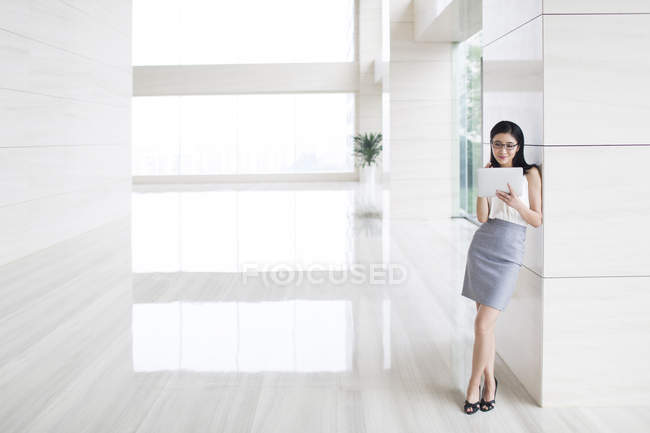 Jeune femme d'affaires utilisant une tablette numérique dans un immeuble de bureaux — Photo de stock