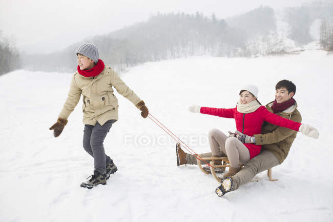 Китайський хлопчик потягнувши сани з батьками на снігу — стокове фото