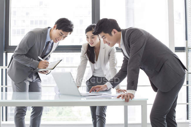 Gente de negocios chinos utilizando el ordenador portátil en sala de reuniones - foto de stock