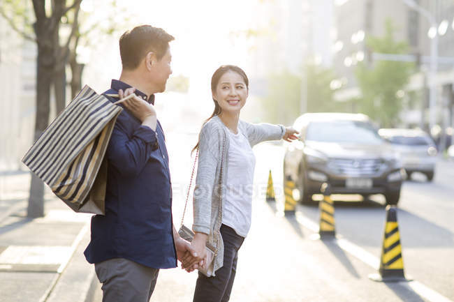 Mature chinese couple on taxi stand after shopping — Stock Photo