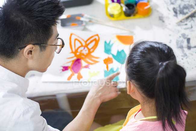 Китайская девушка рисует в художественном классе с учителем — стоковое фото