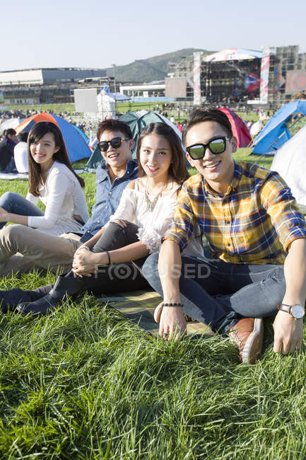 Amici cinesi seduti sull'erba al festival musicale — Foto stock