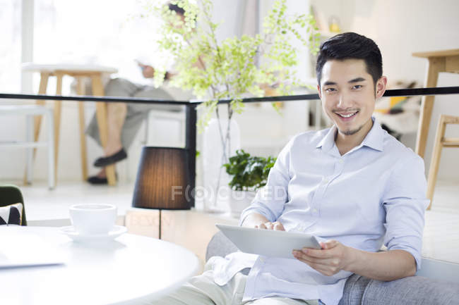 Hombre chino usando tableta digital en la cafetería - foto de stock