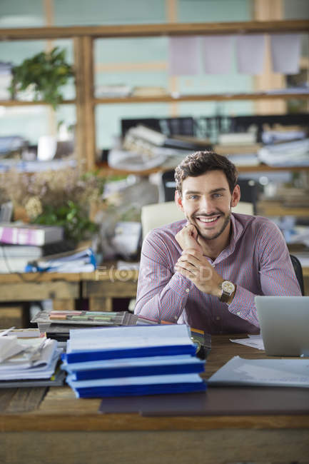 Чоловік офісний працівник сидить за столом і посміхається — стокове фото