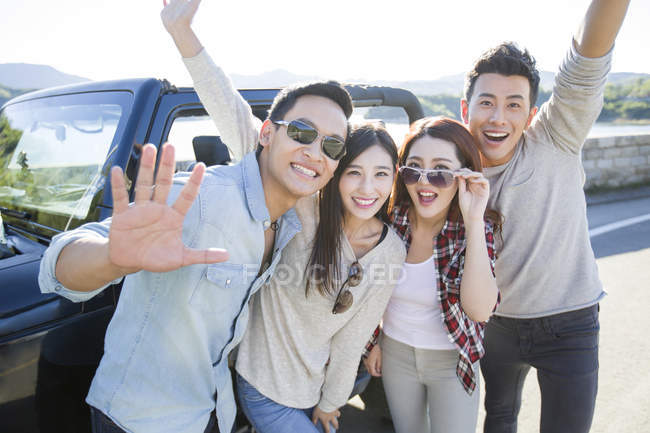 Китайские друзья позируют перед машиной в пригороде — стоковое фото
