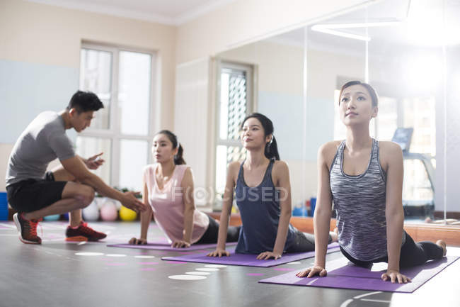 Mujeres asiáticas trabajando con entrenador en el gimnasio - foto de stock