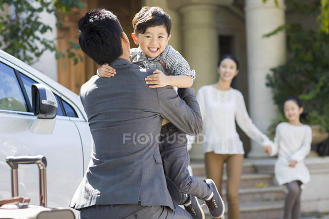 Padre chino sosteniendo y abrazando al hijo en la calle - foto de stock
