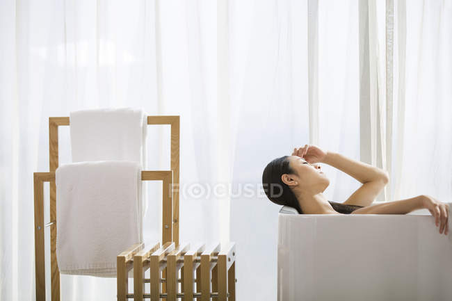 Chinese woman relaxing in bathtub — Stock Photo