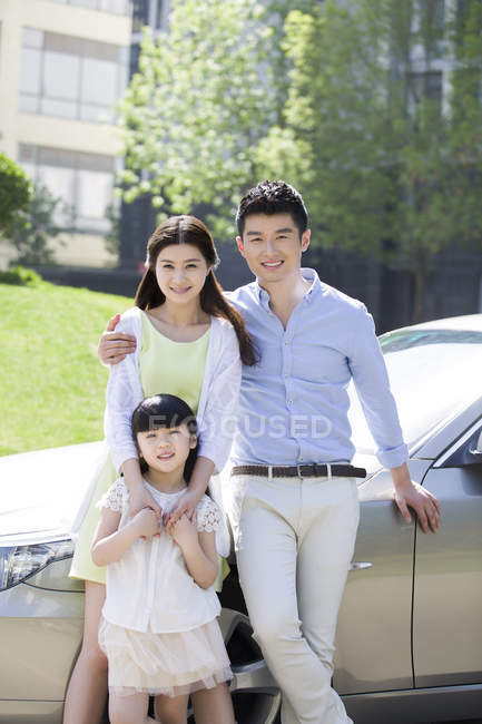 Chinese family posing together in front of car — Stock Photo