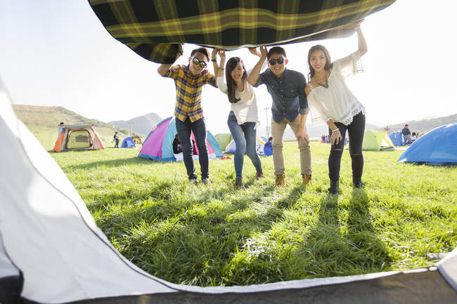 Chinese friends holding blanket by tent entrance — Stock Photo