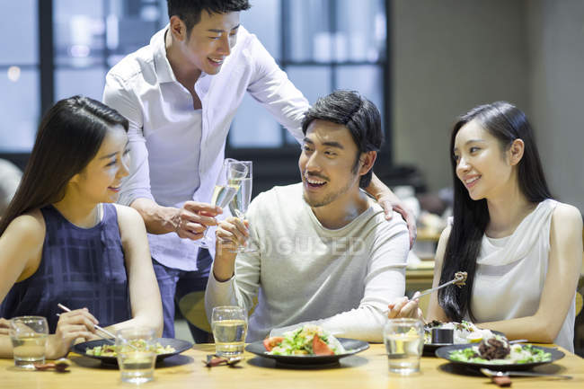 Asian friends clinking glasses at dinner in restaurant — Stock Photo