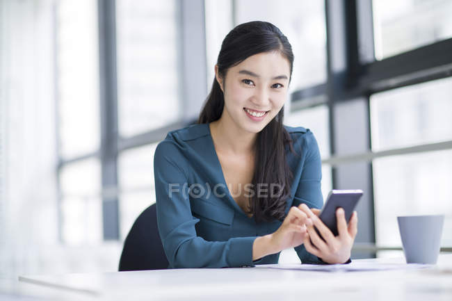 Китайський бізнес-леді за допомогою смартфона в офісі — стокове фото