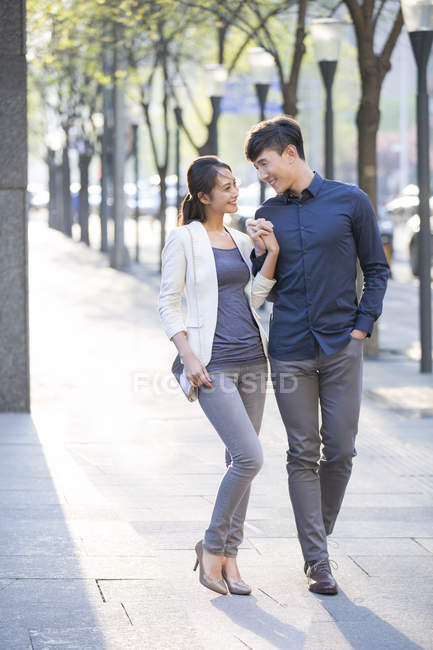 Китайская пара держалась за руки, идя по тротуару — стоковое фото