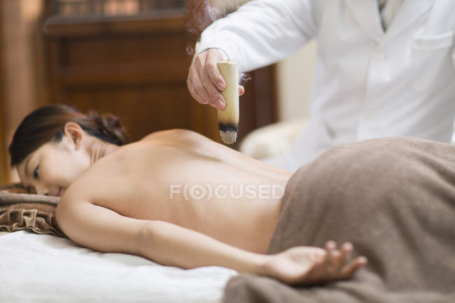 Doctor giving woman moxibustion on massage table — Stock Photo