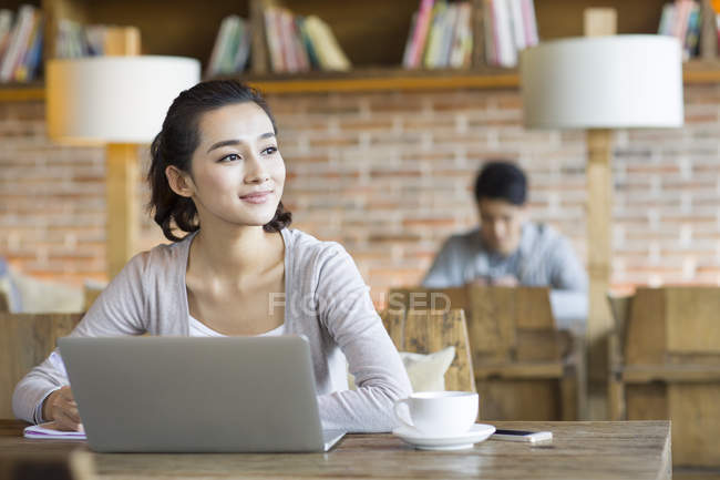 Chinese woman looking through window in cafe — Stock Photo