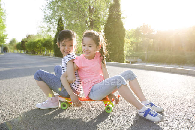 Китайские дети сидят на скейтборде — стоковое фото