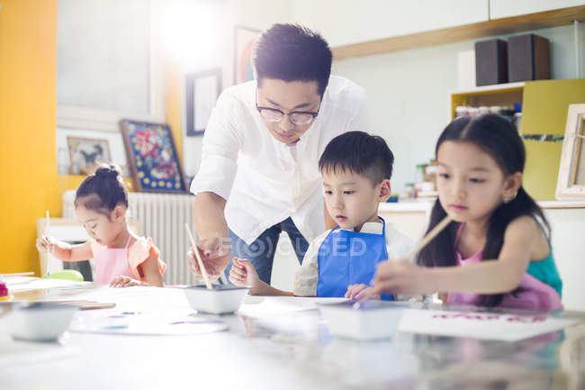Bambini cinesi che dipingono in classe d'arte con insegnante — Foto stock