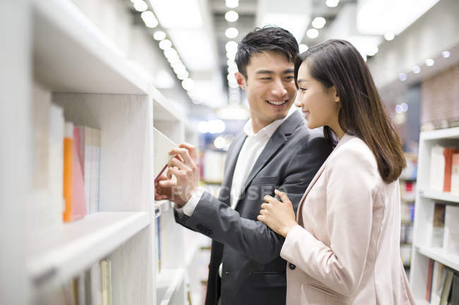 Casal chinês escolhendo livros na livraria — Fotografia de Stock