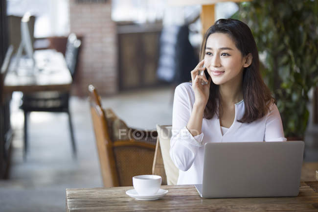 Китайська жінка, що говорять на телефоні в кафе — стокове фото