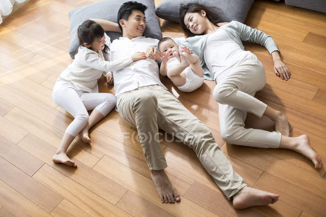 Famiglia cinese a riposo sul pavimento in legno in soggiorno — Foto stock