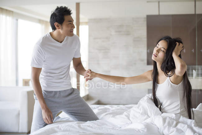 Chino hombre despertando novia en cama - foto de stock