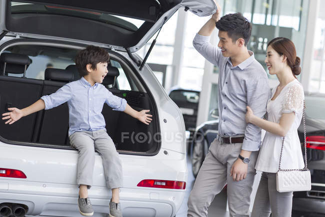 Família chinesa sentada no porta-malas do carro no showroom — Fotografia de Stock