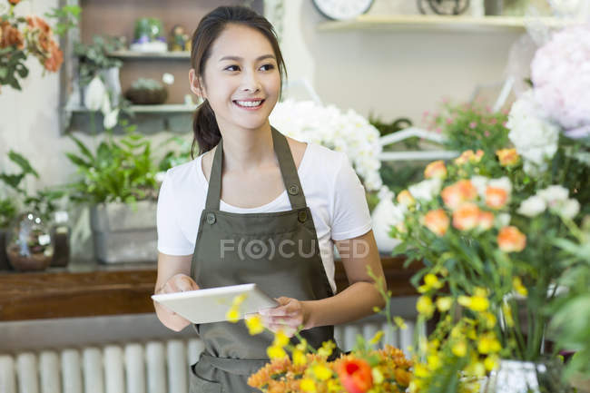 Floristería femenina china usando tableta digital en la tienda - foto de stock