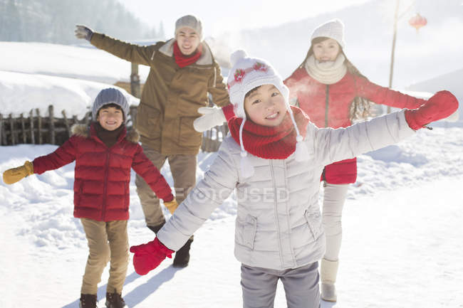 Chinese family posing with arms outstretched in snow — Stock Photo