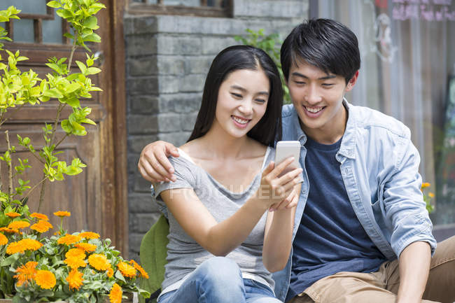 Китайская пара использует смартфон на улице — стоковое фото