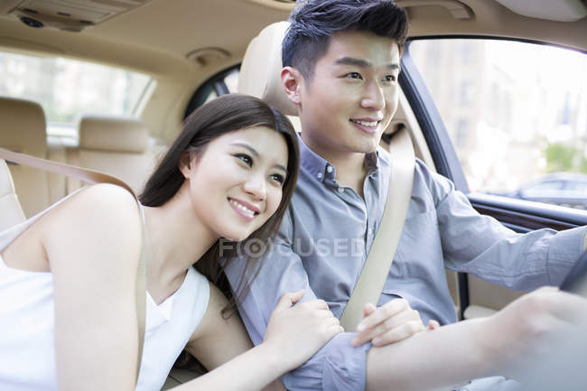 Chinese woman holding male arm in car — Stock Photo
