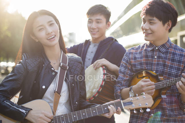 Amigos chineses tocando instrumentos musicais na rua — Fotografia de Stock
