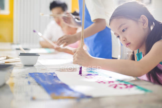 Китайская девушка рисует в художественном классе с учителем — стоковое фото