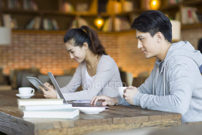 Chinês homem e mulher usando laptop e tablet digital no café — Fotografia de Stock