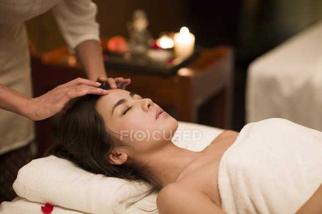 Young Chinese woman receiving facial massage at spa center — Stock Photo