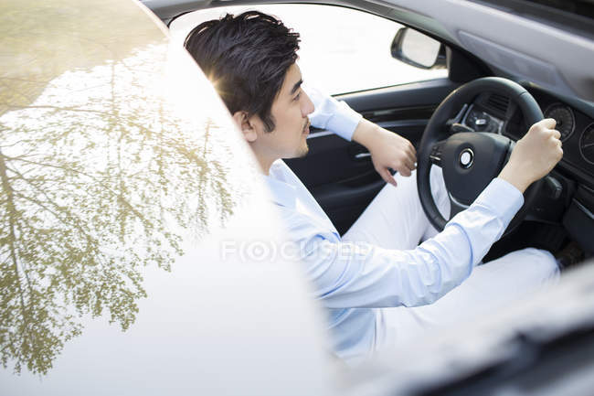 Asiático hombre sentado en coche - foto de stock